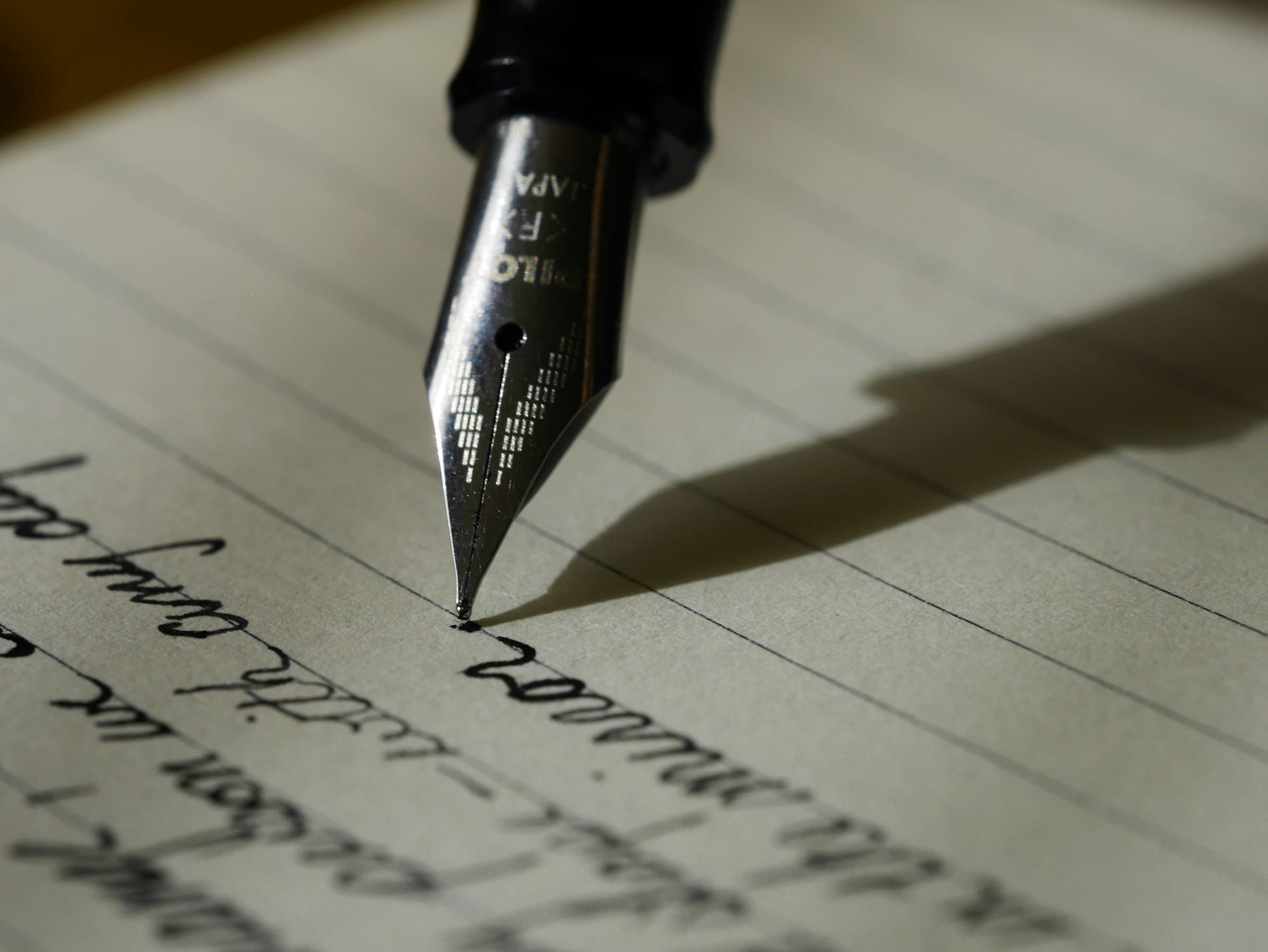 Open notebook and pen on a wooden desk, lit for writing